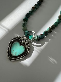 Heart of Love Turquoise Necklace. Decorative setting featuring a beautiful Kingman heart turquoise stone handcrafted in sterling silver. Blue green nuggets stones of Hubei turquoise which are polished enhancing the colors of the stones. This is a one of a kind piece inspired by big love. The necklace measures approximately 18” Sterling silver Pendant and toggle clasp One of a kind. You will receive the necklace pictured. Heart-shaped Turquoise Gemstone Necklace, One Of A Kind Turquoise Heart Jewelry, Turquoise Heart Pendant Jewelry With Natural Stones, Bohemian Heart-shaped Turquoise Necklace With Heart Beads, Turquoise Heart Necklace With Heart Beads, Unique Turquoise Jewelry With Heart Charm, Unique Turquoise Heart-shaped Jewelry, One-of-a-kind Turquoise Heart Jewelry, Unique Heart-shaped Turquoise Jewelry