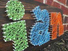 string art is displayed on the side of a brick wall in front of a building