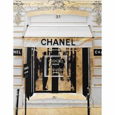 a chanel store front with an advertisement on the door and street signs above it