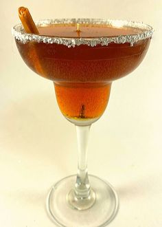 a glass filled with liquid sitting on top of a white table next to a wooden spoon