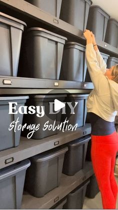 a woman in red pants and white shirt placing plastic bins on shelves with text easy diy storage solution