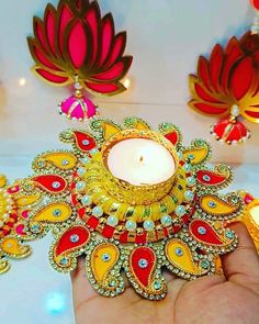 a person holding a candle in their hand with some decorations on the wall behind it