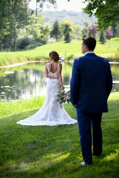 the bride and groom are looking at each other in front of a pond on their wedding day