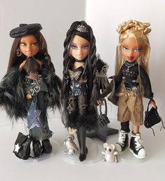 three dolls are standing next to each other on a white surface and one is holding a purse