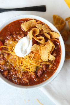 a white bowl filled with chili and tortilla chips on top of a table