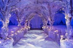 an outdoor wedding venue decorated with white flowers and trees covered in snow, surrounded by candles