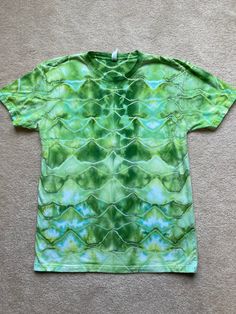 Adult Next Level Size Medium. This shirt was tie dyed by hand in a "snake scale" pattern. Multiple shades of green were used.  Please refer to Next Level size chart or message me to send measurements of the shirt if necessary. When in doubt, size up! Wash before wearing. Wash in cold water by itself or with dark colors only. Air dry or tumble dry low. *please note I do my best to capture accurate photos, but lighting can vary from phone screen to computer screen. Green Casual Tops With Batik Print, Casual Green Batik Print Top, Green Batik Print Top For Summer, Green Cotton Tops With Batik Print, Green Cotton Batik Print Tops, Snake Scale Pattern, Snake Scales, Scale Pattern, A Snake