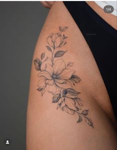 a close up of a woman's thigh with flowers tattooed on the side and behind her