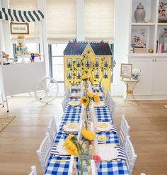 a table set with blue and white checkered cloths, yellow flowers and plates