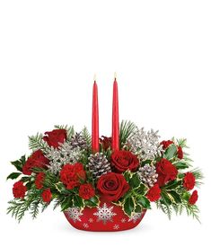 christmas centerpiece with red roses, silver pine cones and two lit candles on white background