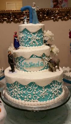 a three tiered cake decorated with snowflakes and figurines