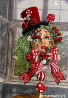 a red and white mask is hanging from a window sill with decorations on it