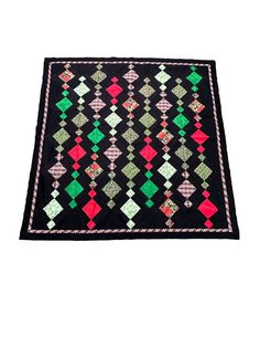 a black rug with red, green and white designs on it's edges is shown