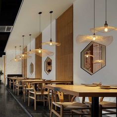 an empty restaurant with wooden tables and chairs, lights hanging from the ceiling over them