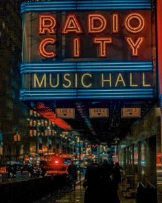 the radio city music hall sign lit up at night