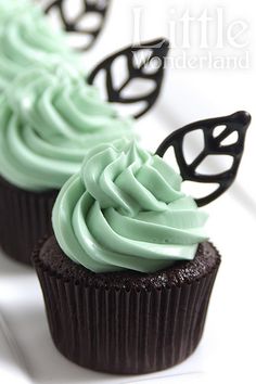 two cupcakes with green frosting and butterfly decorations