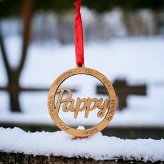 a wooden ornament with the word happy hanging from it's side in the snow