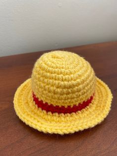 a yellow crocheted hat sitting on top of a wooden table