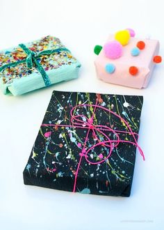 two small gift boxes are decorated with confetti and sprinkles on black paper