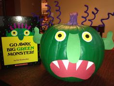 a green monster pumpkin sitting on top of a wooden table next to a book cover