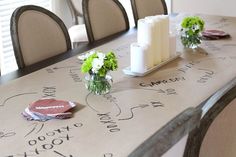 a table with flowers and candles on it in front of a window that has writing all over the table