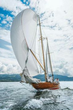 a sailboat sailing on the water under a cloudy sky