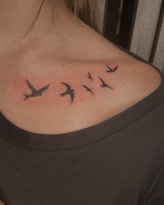 a woman's back shoulder with birds flying in the sky on her left side