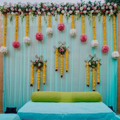 a bed sitting in front of a wall with flowers on it and hanging from the ceiling