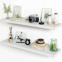 two white floating shelves with books, vases and other items