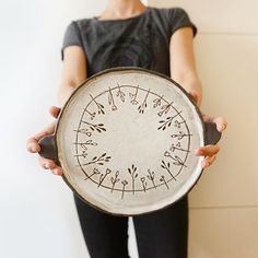 a person holding a plate with designs on it