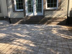 a brick patio with white doors and windows