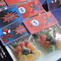 some gummy bears are sitting on a plate with spiderman stickers in them