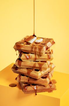 a stack of waffles with syrup dripping from them on a yellow table top