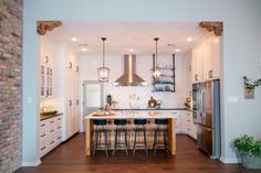 an open kitchen with white cabinets and wood flooring is seen from the doorway to the dining room