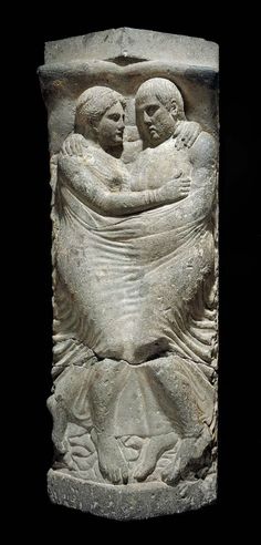 an ancient sculpture with two people hugging each other