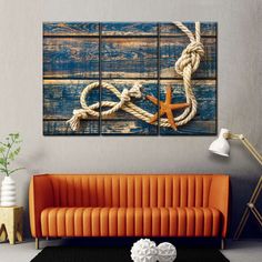 an orange couch sitting in front of a wall with two pieces of art on it