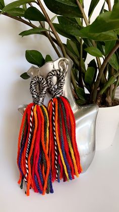 a pair of zebra print tasseled earrings sitting next to a potted plant