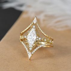 a gold ring with a white diamond surrounded by smaller diamonds on top of the band