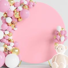 a teddy bear sitting in front of a pink balloon arch