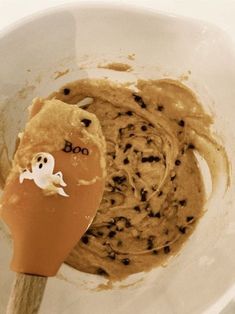 a mixing bowl filled with batter and chocolate chip cookies for halloween treats, with a spoon in it