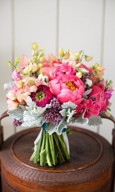 a bouquet of flowers sitting on top of a wooden table next to a cell phone