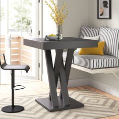 a black table and chair in a white room with striped pillows on the couches