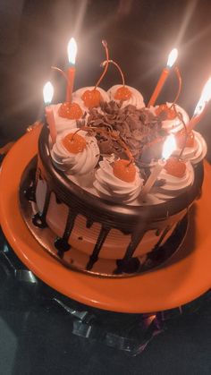 a birthday cake with lit candles on an orange plate