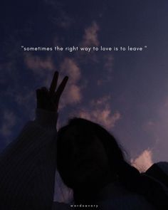 a woman is making the peace sign with her hand while she stands in front of clouds