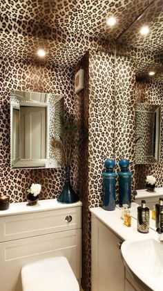 a bathroom with leopard print wallpaper and white vanity tops, blue vases on the sink