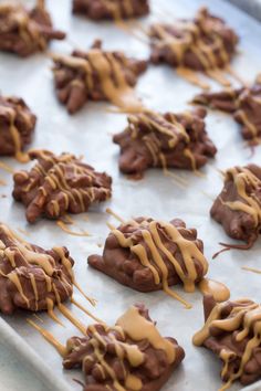 chocolate covered cookies with caramel drizzled on them sitting on a baking sheet