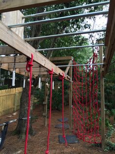 red ropes are tied to the top of a wooden structure in an outdoor play area