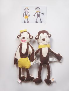 two monkey stuffed animals sitting next to each other on a white surface with an advertisement above them