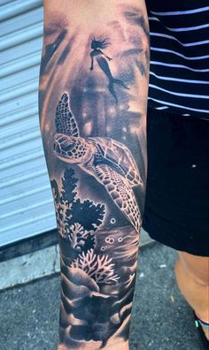 a man with a tattoo on his arm that has a sea turtle and corals