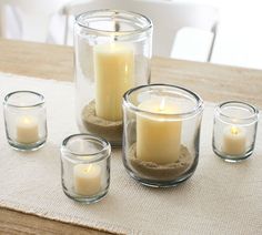 candles are placed in glass containers on a table